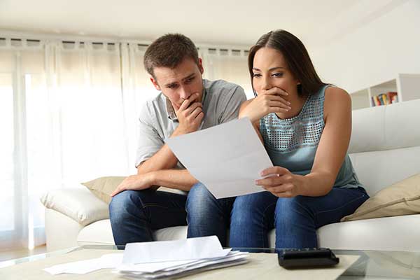 troubled couple reviewing a document on the couch